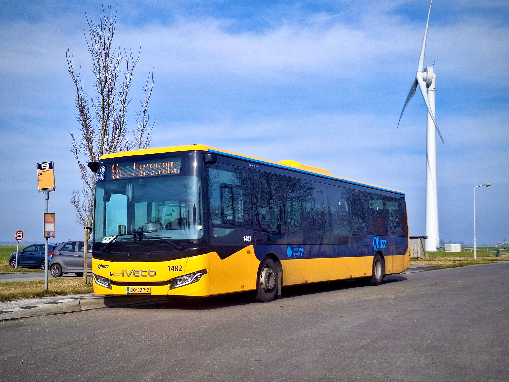 Lijn 95 staat stil bij een halte met een windmolen op de achtergrond