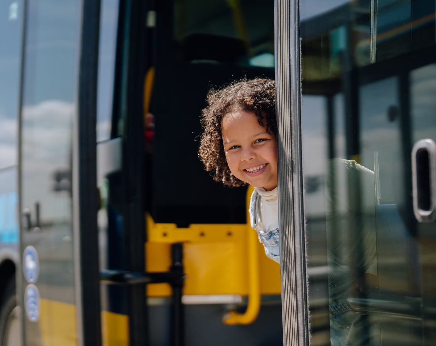 Klein kind kijkt glimlachend bij de deuropening naar buiten